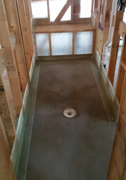 Long shower pan with the membrane turned up both side walls to a level line, open drain flange set in the sloped floor