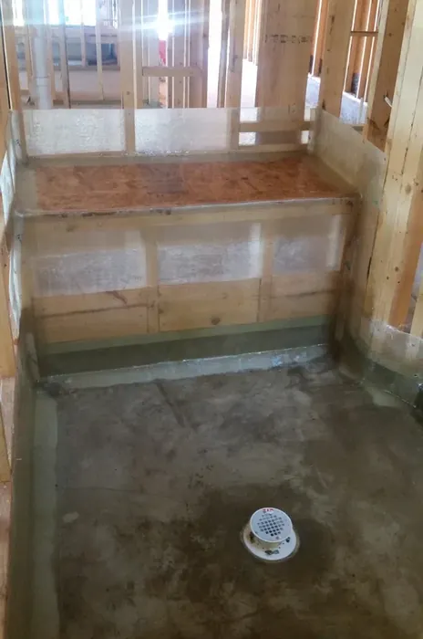 Shower pan with a built-in bench, the membrane wrapping the bench face and top without a joint